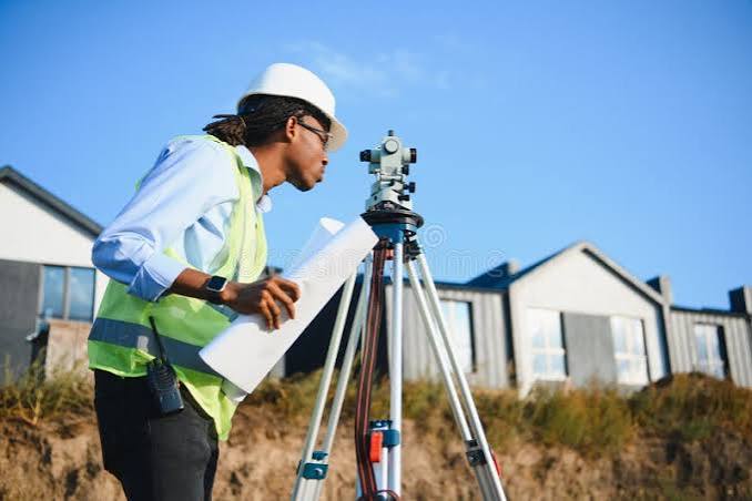 Surveyor reading plans next to a theodolite